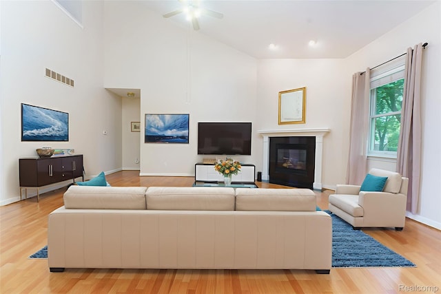 34444 Fargo St, Livonia, MI 48152 - living room with light wood-style floors, ceiling fan, a fireplace with flush hearth, and high vaulted ceiling