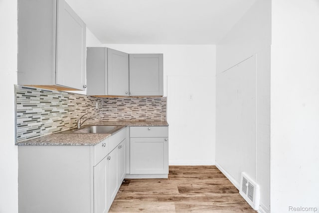 20069 Goulburn St, Detroit, MI 48205 - kitchen with a sink, light wood-style flooring, decorative backsplash, and gray cabinets