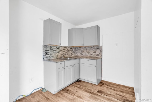 20069 Goulburn St, Detroit, MI 48205 - kitchen featuring a sink, light wood-style floors, decorative backsplash, gray cabinets, and light countertops