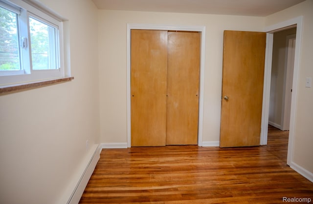 46254 Custer Ave, Utica, MI 48317 - unfurnished bedroom featuring wood finished floors, a closet, and a baseboard heating unit