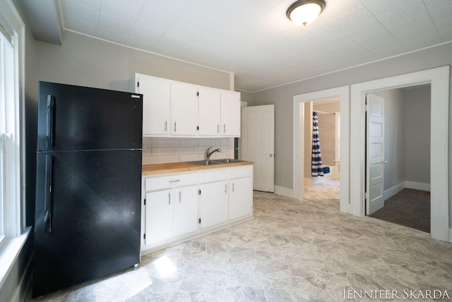 884 Emerson Ave, Muskegon, MI 49442 - kitchen with freestanding refrigerator, a sink, white cabinets, backsplash, and butcher block countertops