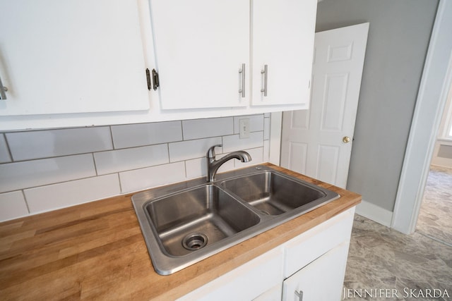 884 Emerson Ave, Muskegon, MI 49442 - kitchen with a sink, white cabinets, backsplash, light countertops, and baseboards