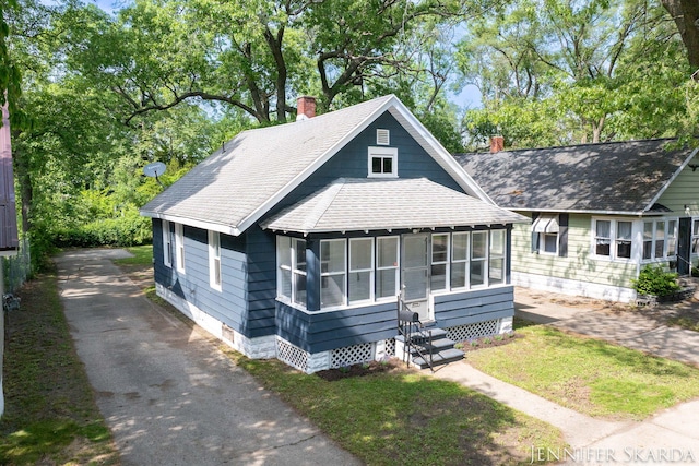 884 Emerson Ave, Muskegon, MI 49442 - view of front of property with a chimney, roof with shingles, a sunroom, entry steps, and crawl space