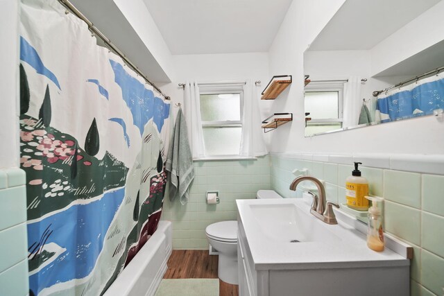 2618 Greencliff Dr, East Lansing, MI 48823 - bathroom featuring wood finished floors, tile walls, vanity, toilet, and shower / bath combo with shower curtain