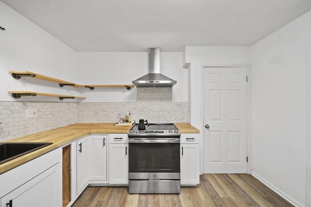 2618 Greencliff Dr, East Lansing, MI 48823 - kitchen featuring stainless steel range with electric cooktop, wall chimney range hood, butcher block counters, and light wood-style flooring