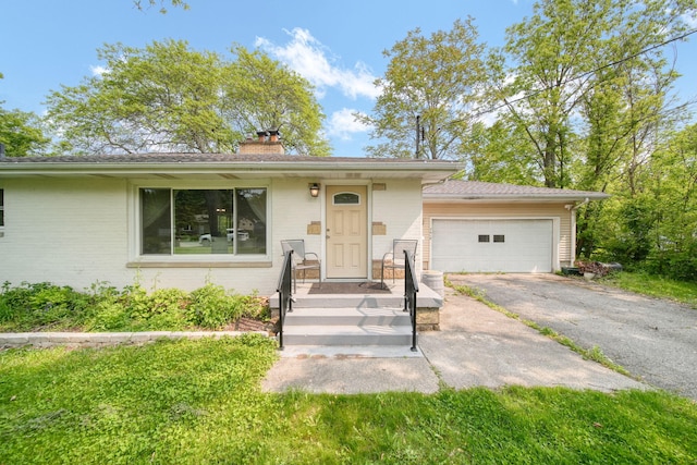 2618 Greencliff Dr, East Lansing, MI 48823 - view of front of home with a chimney, a garage, asphalt driveway, and brick siding