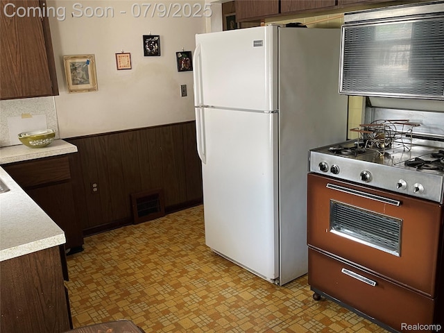 6250 Grandville Ave, Detroit, MI 48228 - kitchen featuring stove, freestanding refrigerator, light countertops, wainscoting, and light flooring