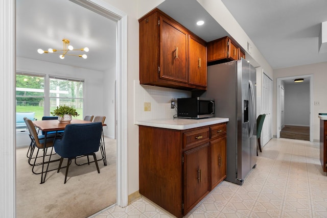 3673 Pheasant Dr, Ann Arbor, MI 48103 - kitchen with stainless steel fridge, light countertops, tasteful backsplash, a chandelier, and brown cabinetry
