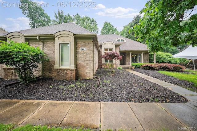 8487 Sherwood Dr, Grosse Ile, MI 48138 - view of front of home with brick siding, covered porch, and a shingled roof