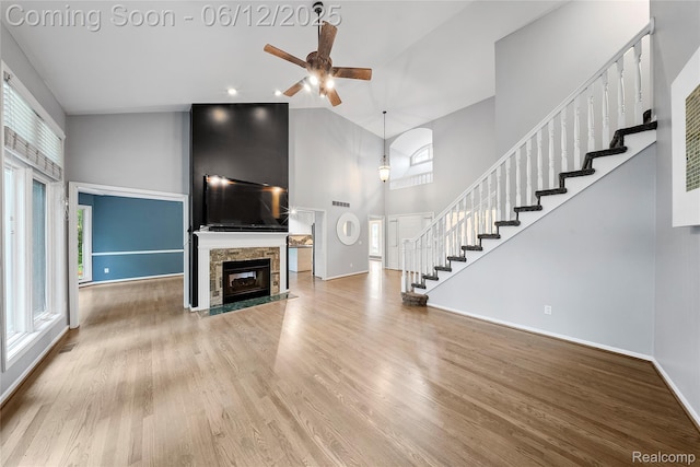 8487 Sherwood Dr, Grosse Ile, MI 48138 - unfurnished living room featuring a towering ceiling, a ceiling fan, stairs, wood finished floors, and healthy amount of natural light