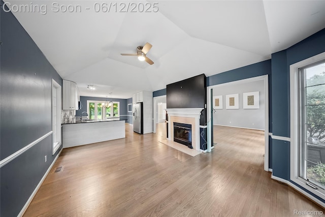 8487 Sherwood Dr, Grosse Ile, MI 48138 - unfurnished living room with a ceiling fan, vaulted ceiling, light wood-type flooring, plenty of natural light, and a fireplace with flush hearth