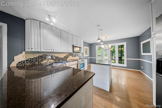 8487 Sherwood Dr, Grosse Ile, MI 48138 - kitchen with a sink, appliances with stainless steel finishes, light wood-style floors, backsplash, and white cabinetry