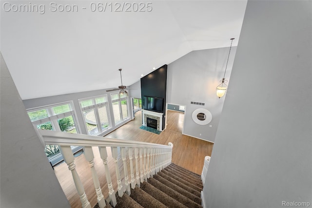 8487 Sherwood Dr, Grosse Ile, MI 48138 - staircase featuring ceiling fan, wood finished floors, high vaulted ceiling, and a fireplace with flush hearth
