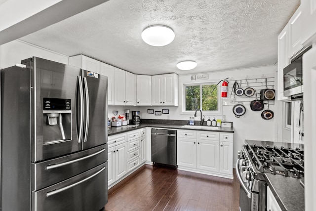 5886 13 Mile Rd, Remus, MI 49340 - kitchen featuring appliances with stainless steel finishes, dark countertops, a sink, and a textured ceiling