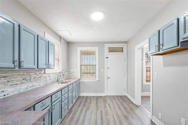 3054 Cadillac Blvd, Redford, MI 48214 - kitchen with a sink, light wood-style flooring, a textured ceiling, backsplash, and baseboards