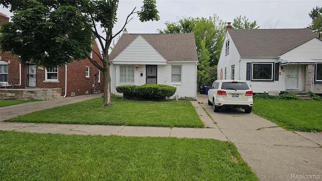 19610 Westphalia St, Detroit, MI 48205 - bungalow with brick siding, a front lawn, concrete driveway, and roof with shingles