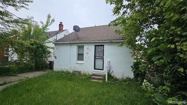 19610 Westphalia St, Detroit, MI 48205 - rear view of house featuring entry steps, roof with shingles, brick siding, and a lawn