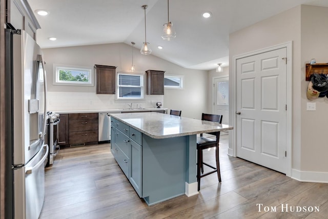 158 Brewer Park Cir, Grand Rapids, MI 49548 - kitchen with stainless steel appliances, a sink, a kitchen breakfast bar, light wood finished floors, and vaulted ceiling