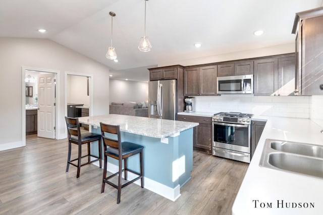 158 Brewer Park Cir, Grand Rapids, MI 49548 - kitchen with appliances with stainless steel finishes, a kitchen island, light wood-type flooring, dark brown cabinetry, and a kitchen bar