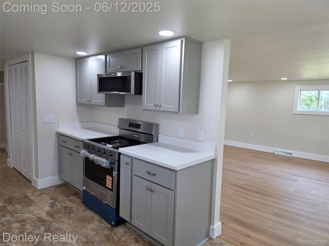 4514 Sebewaing Rd, Owendale, MI 48754 - kitchen with stainless steel appliances, gray cabinets, baseboards, light countertops, and light wood-style floors