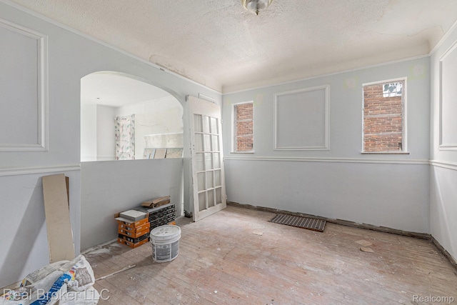 9236 Manistique St, Detroit, MI 48224 - empty room with a textured ceiling, arched walkways, and hardwood / wood-style floors