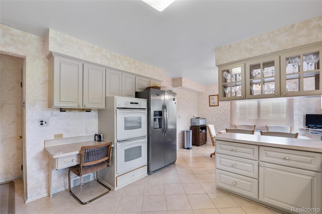 22840 Twyckingham Way, Addison, MI 48034 - kitchen featuring stainless steel fridge, double oven, wallpapered walls, light countertops, and light tile patterned floors