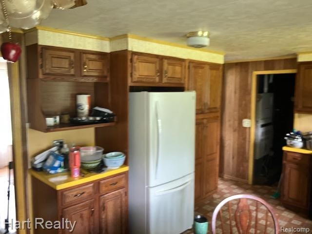 138 W Hunters Creek Rd, Lapeer, MI 48446 - kitchen with freestanding refrigerator, light countertops, brown cabinets, and wooden walls
