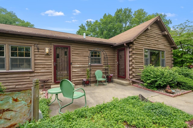 987 Wagner Dr, Battle Creek, MI 49017 - view of front facade with a patio area, log exterior, and a shingled roof