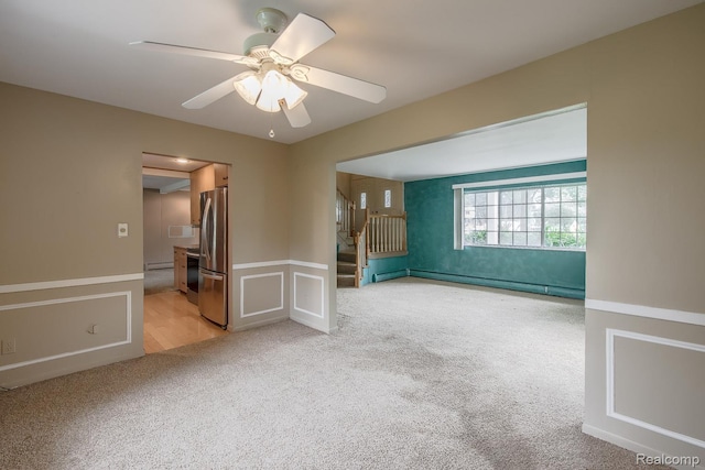 1231 Duckwood Ct, White Lake, MI 48383 - empty room featuring light colored carpet, wainscoting, a ceiling fan, stairs, and baseboard heating