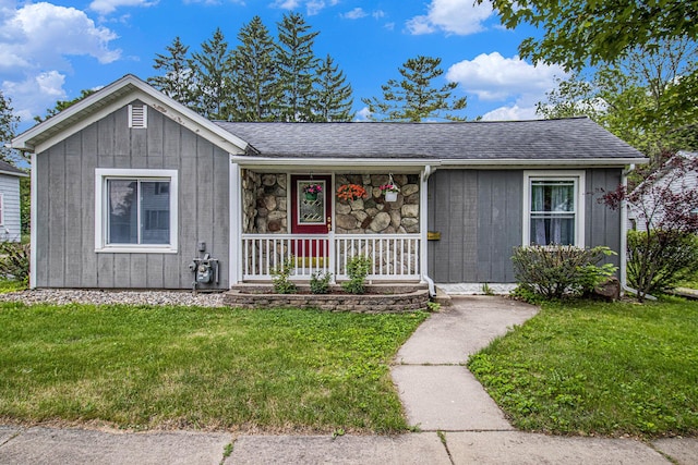 512 Clark St, Big Rapids, MI 49307 - view of front facade featuring covered porch, a front yard, a shingled roof, board and batten siding, and stone siding