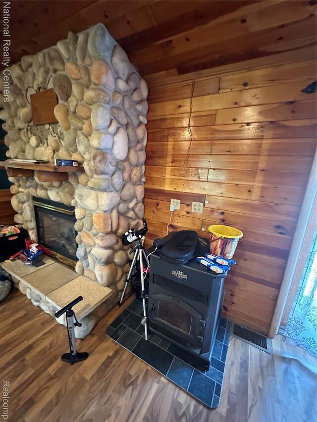 5150 Lafave Rd, Black River, MI 48721 - detailed view of a wood stove, wood finished floors, a fireplace, wood ceiling, and wooden walls