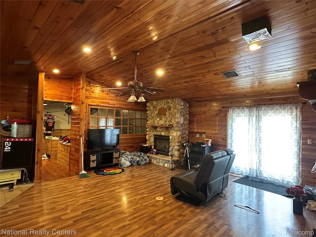 5150 Lafave Rd, Black River, MI 48721 - living room with a ceiling fan, a stone fireplace, wood finished floors, wood ceiling, and wood walls