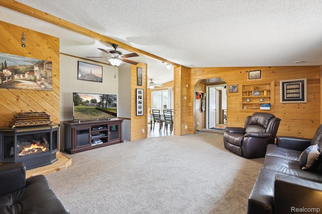 2536 Meridian Rd, Lewiston, MI 49756 - carpeted living room featuring wood walls, a ceiling fan, a textured ceiling, a multi sided fireplace, and beamed ceiling