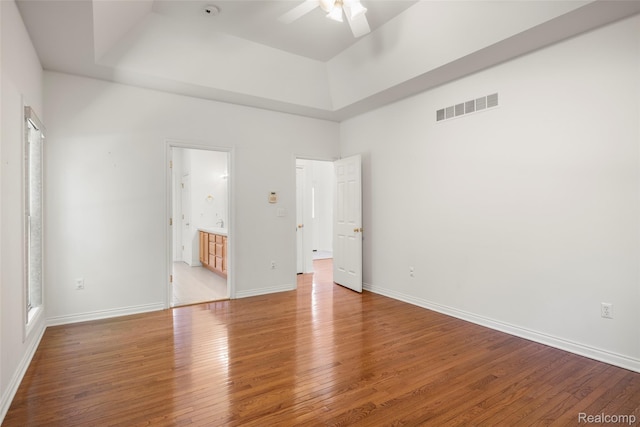 3409 Ancient Dr, Port Huron, MI 48060 - unfurnished bedroom featuring a raised ceiling, wood finished floors, connected bathroom, and ceiling fan