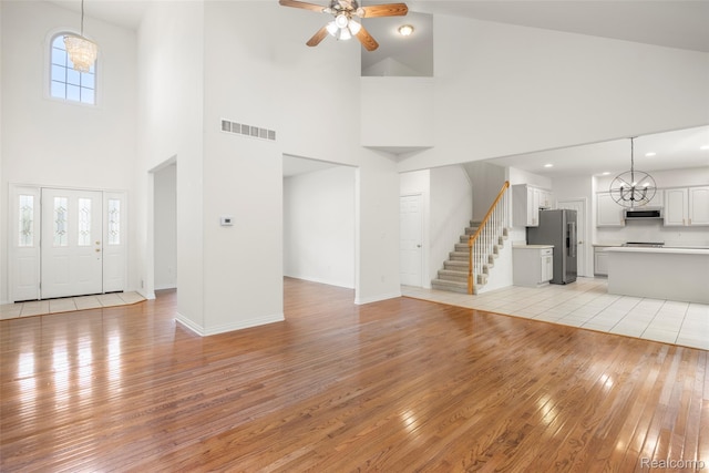 3409 Ancient Dr, Port Huron, MI 48060 - unfurnished living room with a high ceiling, light wood-style flooring, stairway, a chandelier, and ceiling fan