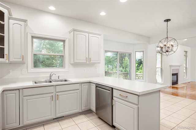 3409 Ancient Dr, Port Huron, MI 48060 - kitchen with dishwasher, a peninsula, light tile patterned flooring, a chandelier, and light countertops