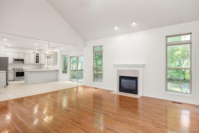 3409 Ancient Dr, Port Huron, MI 48060 - unfurnished living room featuring light wood-style flooring, a tile fireplace, plenty of natural light, recessed lighting, and high vaulted ceiling