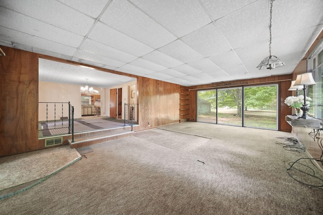 538 S Jackson St, Hanover, MI 49241 - unfurnished living room featuring a chandelier, wood walls, carpet floors, and a drop ceiling