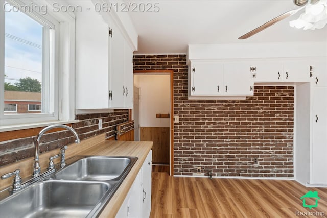 32703 Anita Dr, Westland, MI 48185 - kitchen featuring brick wall, white cabinets, a ceiling fan, light wood-style floors, and light countertops