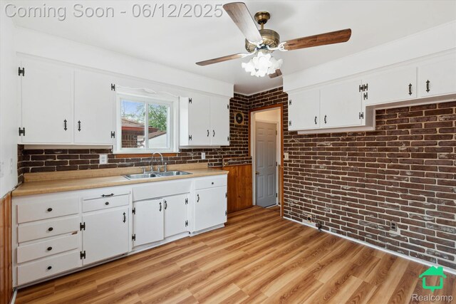 32703 Anita Dr, Westland, MI 48185 - kitchen with light countertops, white cabinetry, a ceiling fan, brick wall, and light wood-style flooring