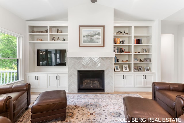 18153 Newgate Ln, Spring Lake, MI 49456 - living area featuring a tile fireplace, light wood-type flooring, built in shelves, and lofted ceiling