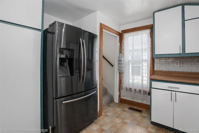 2931 4th St, Trenton, MI 48183 - kitchen featuring black fridge, healthy amount of natural light, tasteful backsplash, and white cabinets
