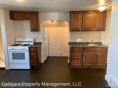 22174 Cushing Ave, Eastpointe, MI 48021 - kitchen featuring white gas stove, tasteful backsplash, brown cabinetry, and a sink