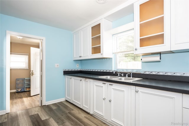 2910 Peerless Ave, Waterford, MI 48328 - kitchen with a sink, dark countertops, dark wood-style flooring, white cabinetry, and glass insert cabinets