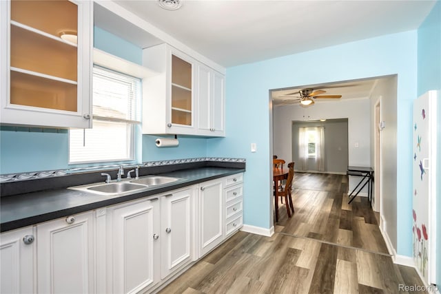 2910 Peerless Ave, Waterford, MI 48328 - kitchen with a sink, dark countertops, white cabinets, wood finished floors, and plenty of natural light