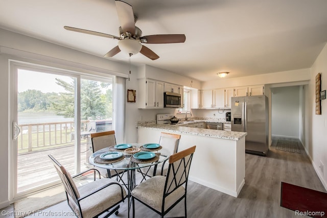 4851 Shoreline Blvd, Waterford, MI 48329 - kitchen featuring appliances with stainless steel finishes, a peninsula, ceiling fan, wood finished floors, and white cabinets
