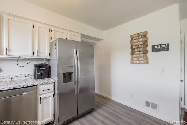 4851 Shoreline Blvd, Waterford, MI 48329 - kitchen with appliances with stainless steel finishes, light wood-style flooring, baseboards, white cabinetry, and light stone counters
