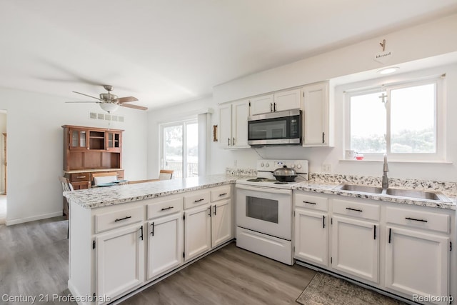4851 Shoreline Blvd, Waterford, MI 48329 - kitchen featuring stainless steel microwave, white electric range oven, a sink, a peninsula, and white cabinets