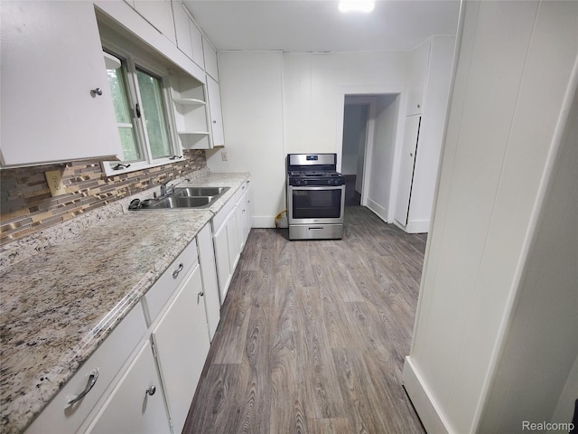 1505 Downey St, Flint, MI 48503 - kitchen featuring stainless steel gas stove, a sink, light wood-style flooring, white cabinets, and backsplash