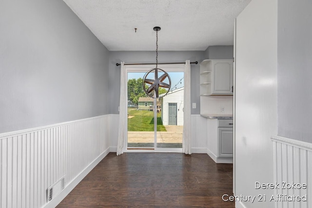 4246 Flamingo Ave SW, Wyoming, MI 49509 - unfurnished dining area featuring a chandelier, dark wood-type flooring, wainscoting, and a textured ceiling